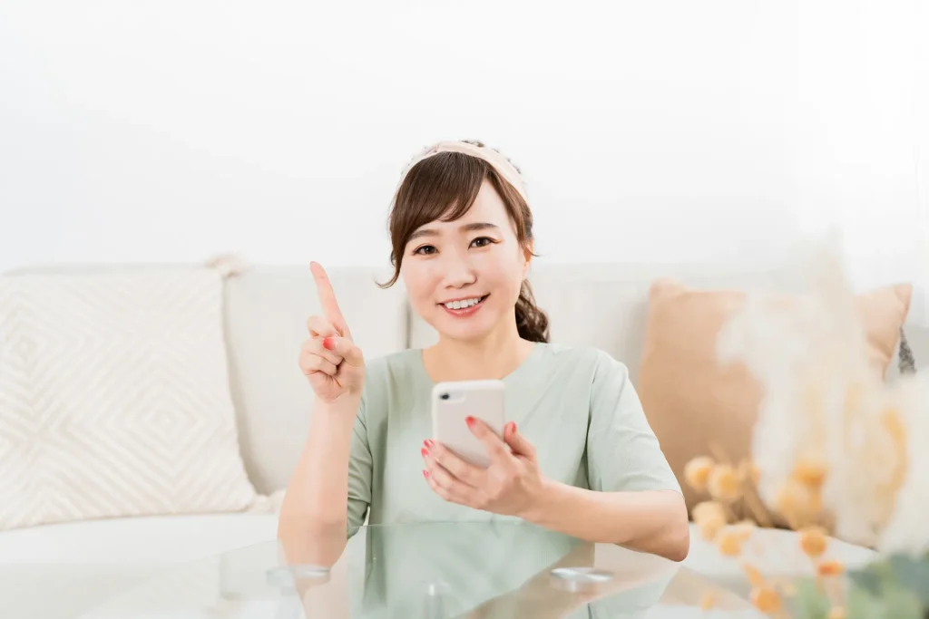 家でスマホを使う笑顔の日本人女性