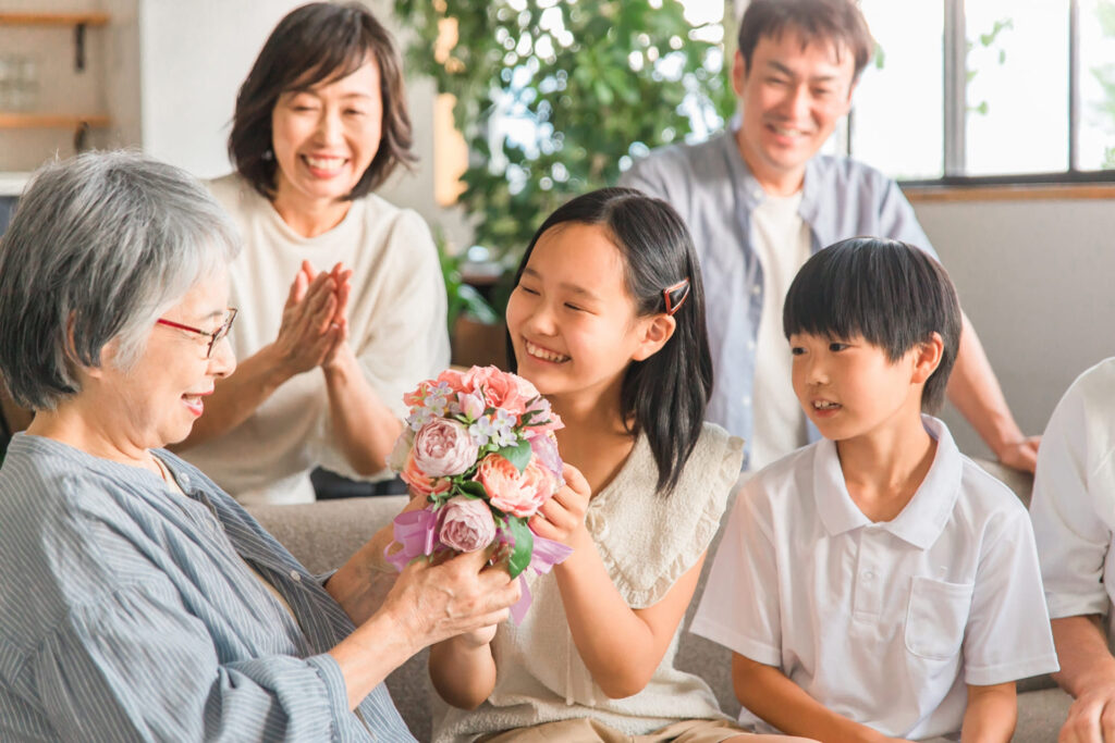 孫から花束をもらう高齢者女性 (1)