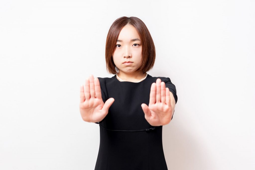 制止するジェスチャーをする礼服を来た女性