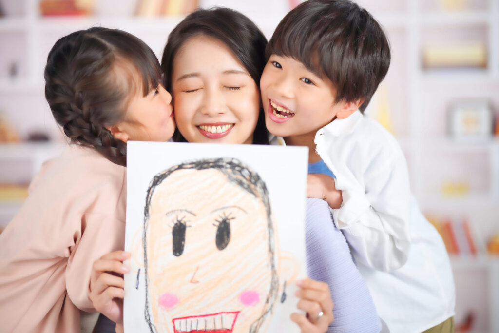 似顔絵を持った母とくっつく子供たち